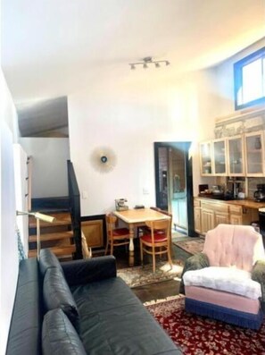 Un espacio habitable compacto con sofá, mesa de comedor y kitchenette.