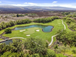En golfbane med flere bunkers, vandhuller og en snoet sti.