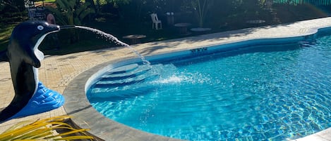 A swimming pool with a dolphin statue spraying water.