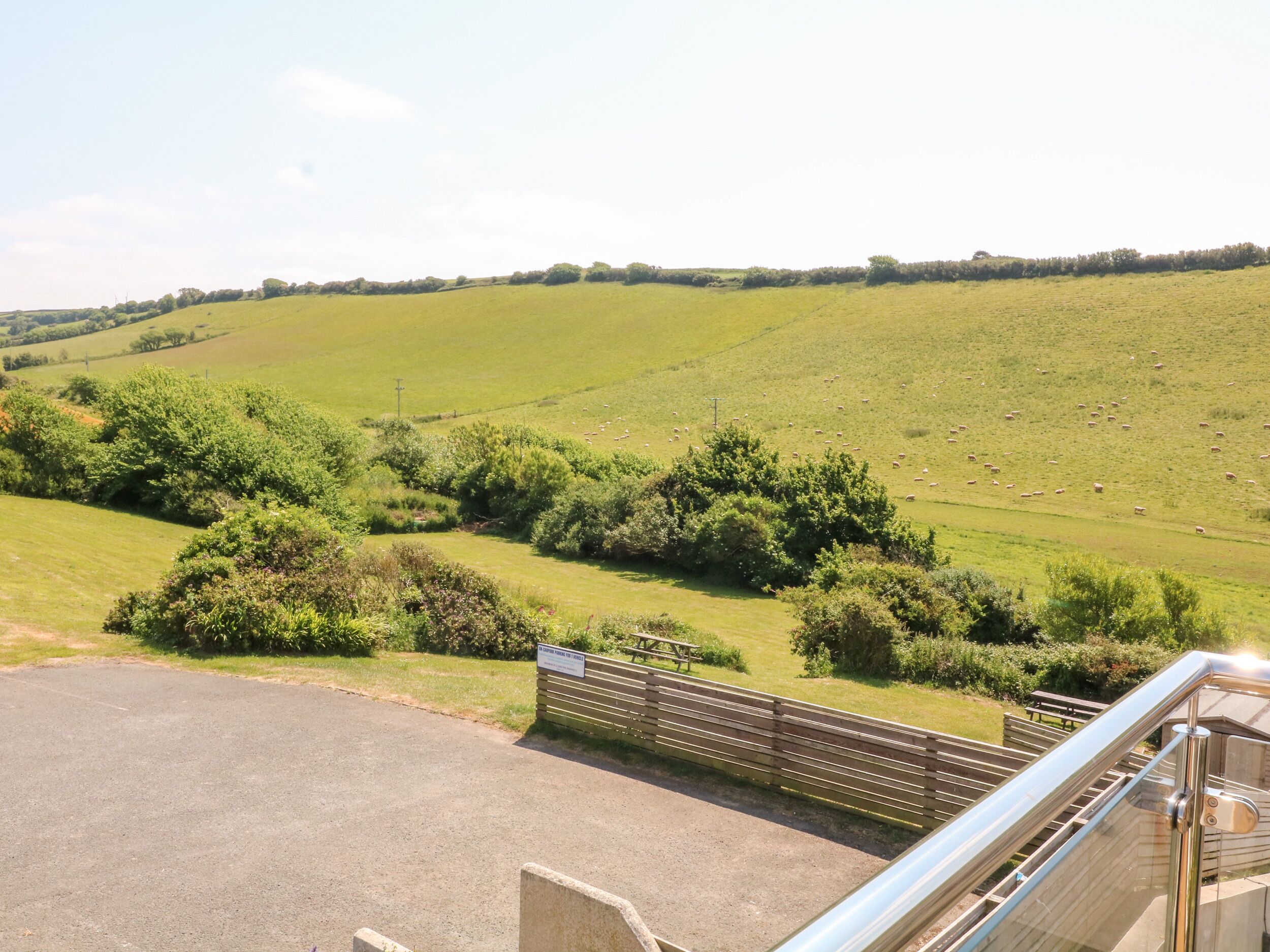 A view of a green field with a fence and a picnic table.