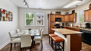 A modern kitchen with wooden cabinets, a granite countertop, and a dining area with a glass table and chairs.