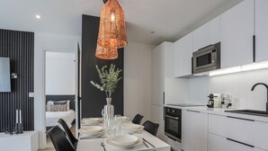 A modern kitchen with white cabinets, a microwave, and a coffee machine. - Appartement Ebène - Welkey (Antibes)