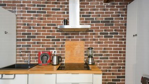 A kitchen with a brick wall, a wooden countertop, a coffee maker, a kettle, and a blender. - Studio Rostène - Welkeys (Paris)