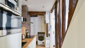 A compact kitchen with a modern stove, a coffee maker, and a washing machine. - Studio Rostène - Welkeys (Paris)