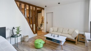 A modern living room with a sofa, a coffee table, a green bean bag, and a lamp. - Studio Rostène - Welkeys (Paris)