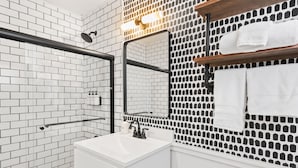A modern bathroom with white subway tiles, a glass shower enclosure, a white sink, and a mirror with a black frame. - Standard Room w/ Two Double Beds, Fireplace Room #10 (Lake Placid)