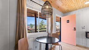 A room with a round table, two chairs, a hanging light fixture, a door with a number, and a window with curtains. - Standard Room w/ Two Double Beds, Fireplace Room #10 (Lake Placid)