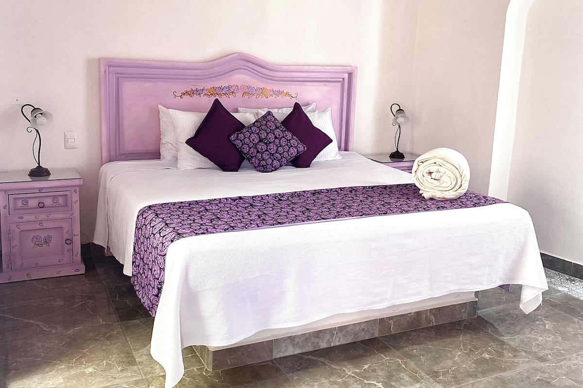 A bedroom with a bed, a nightstand, and a wall-mounted fan.