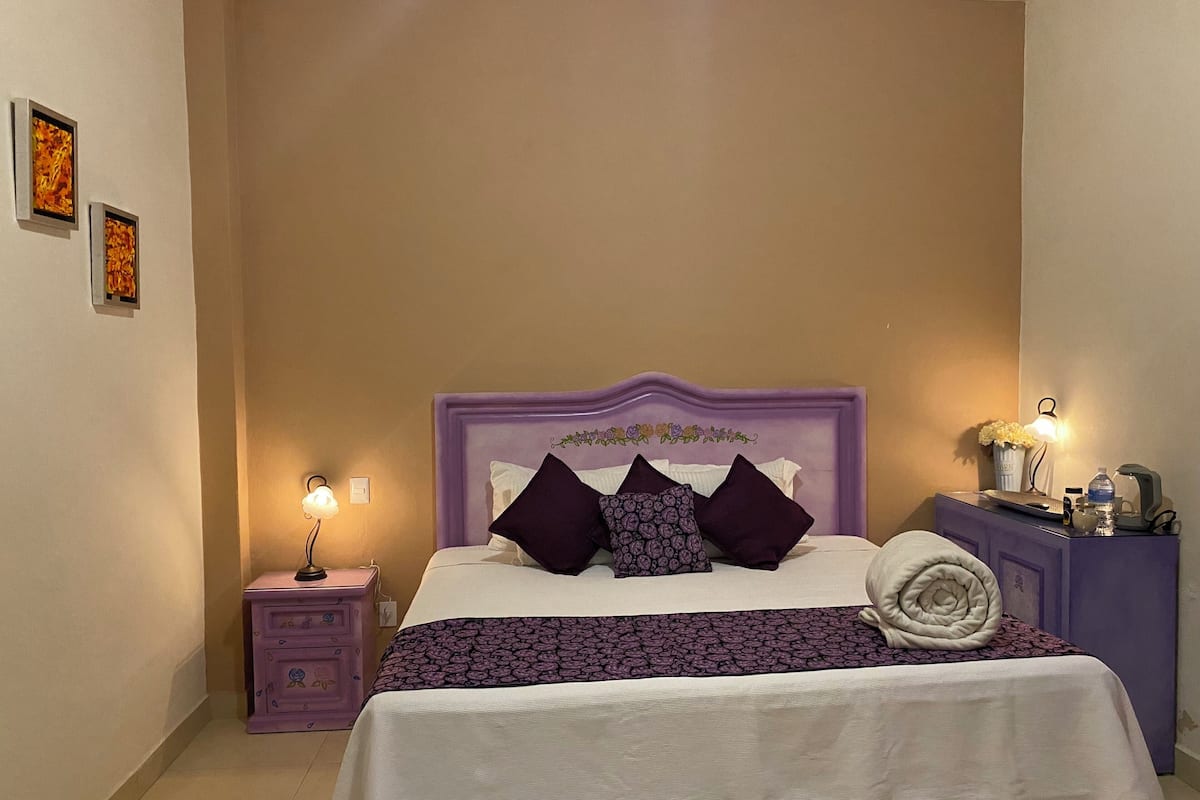 A bedroom with a bed, nightstands, and a dresser.