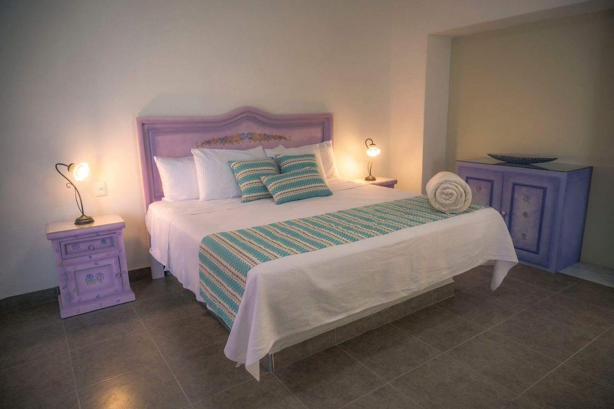 A neatly made bed with a striped blanket, two bedside lamps, and a small nightstand with a lamp.