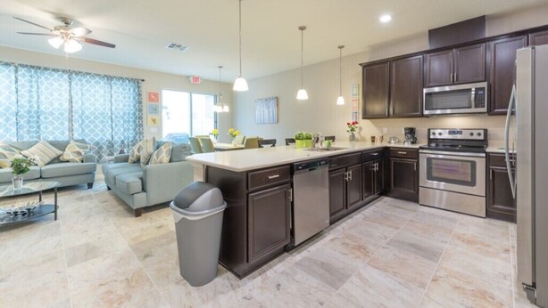 A modern kitchen with dark cabinets, stainless steel appliances, and a central island. - Spacious 4BR Kissimmee Townhome in Osceola County, perfect for families! (Kissimmee)