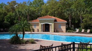 A poolside area with a building, palm trees, and lounge chairs. - Spacious 4BR Kissimmee Townhome in Osceola County, perfect for families! (Kissimmee)