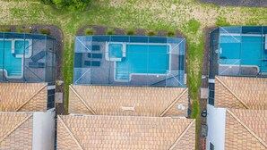 Una zona residenziale con diverse piscine, ognuna caratterizzata da un design geometrico particolare e circondata da un prato.
