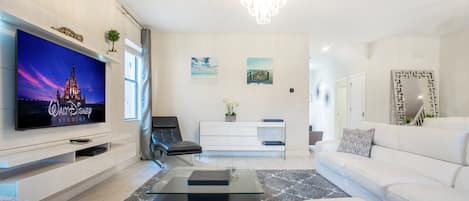 Una sala de estar moderna con televisor de pantalla plana, un sofá, una mesa de centro y una araña.