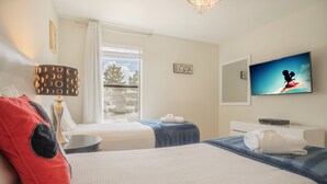 Ein Hotelzimmer mit zwei Betten, einem Fernseher, einem Fenster mit Vorhängen und einer Lampe.