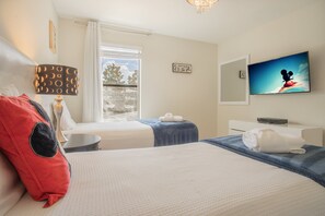 Ein Hotelzimmer mit zwei Betten, einem Fernseher, einem Fenster mit Vorhängen und einer Lampe.