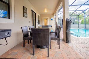 An outdoor patio with wicker furniture, a pool, and a grill.