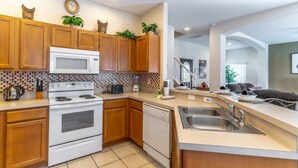 A modern kitchen with wooden cabinets, a microwave, stove, and dishwasher. - Charming 4-bedroom villa in Clermont's High Grove, near Disney, with private pool. (Clermont)