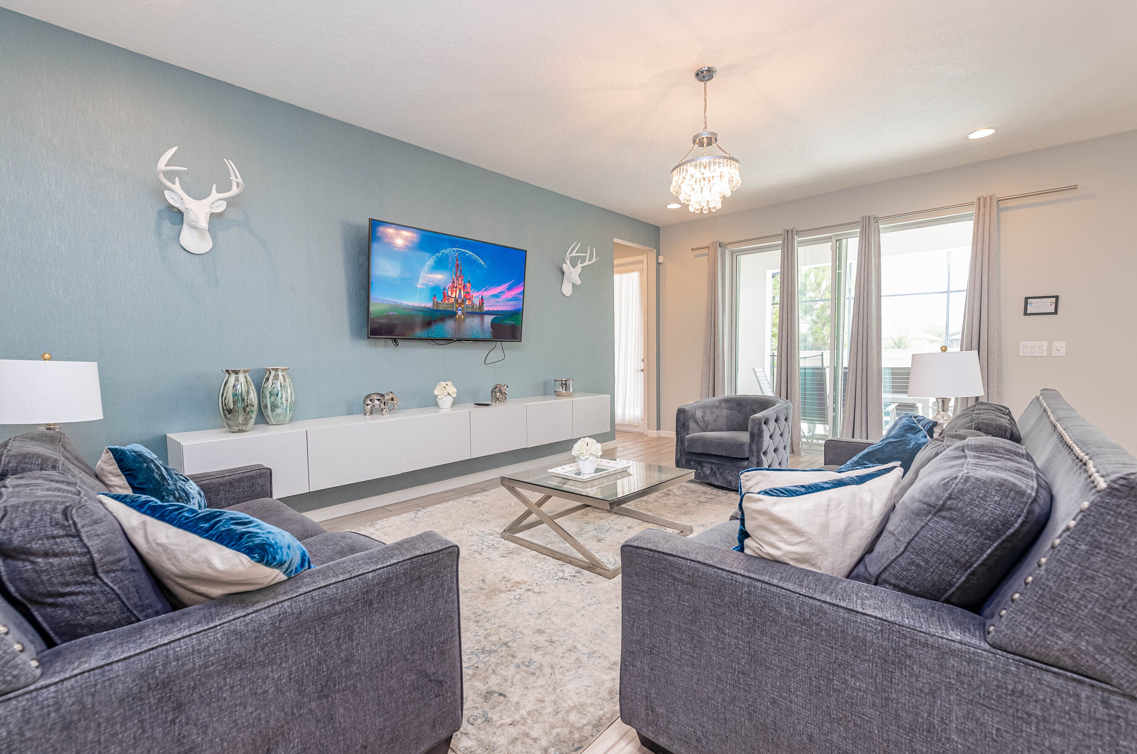 Een moderne woonkamer met een grijze zithoek, een glazen salontafel en een tv met een prachtig uitzicht op het scherm.