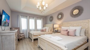 Habitación de hotel con dos camas, televisión, escritorio y candelabro.