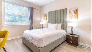 A modern bedroom with a large bed, two bedside tables, a chair, and artwork on the walls. - Spacious 3BR condo in Orlando, perfect for families, near attractions. (Orlando)