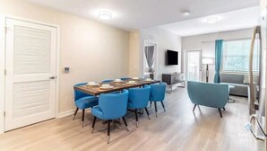 A modern living room with a dining area, a flat-screen TV, and a sofa. - Spacious 3BR condo in Orlando, perfect for families, near attractions. (Orlando)