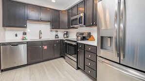 Una cocina moderna con armarios de madera oscura, electrodomésticos de acero inoxidable y encimera de color claro.