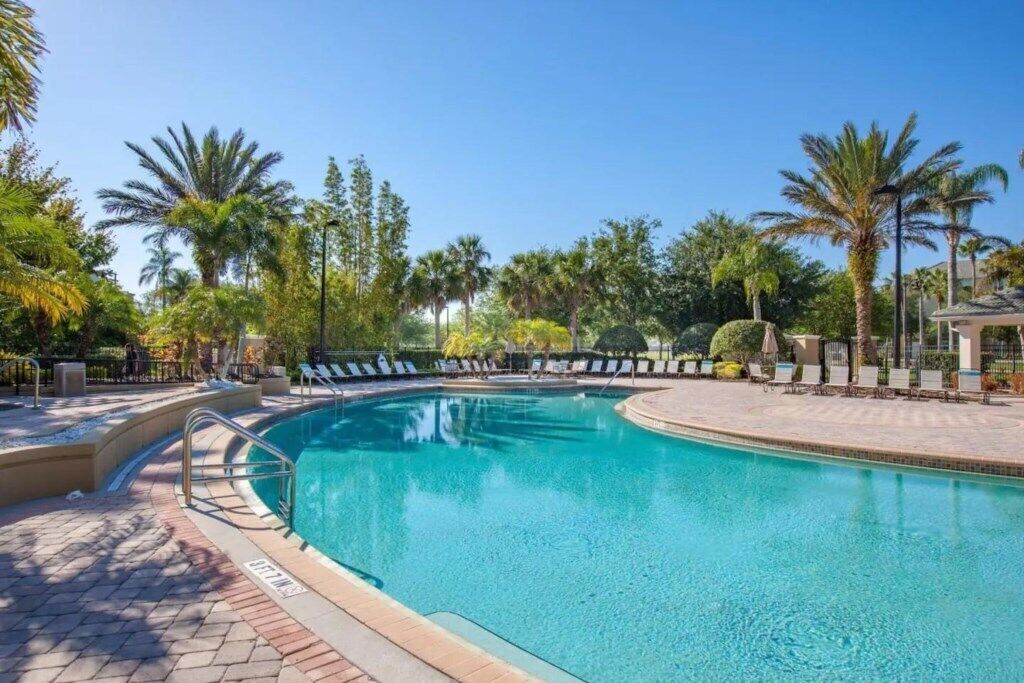 Una piscina con sillas de descanso y palmeras.