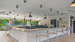 Un área de bar moderna con una isla central, taburetes y lámparas colgantes.