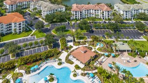 Un complejo turístico con varias edificaciones, una gran piscina y un lago al fondo.