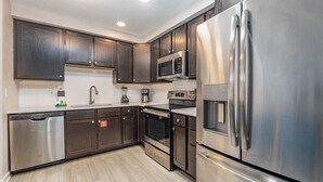 Una cocina moderna con armarios de madera oscura, electrodomésticos de acero inoxidable y piso de madera clara.