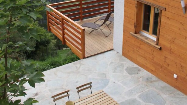 A wooden cabin with a stone patio, a wooden deck, and a table with chairs. - Outside: 4-person chalet with balcony, terrace with garden furniture, breathtaking views of the Val (St-Luc)