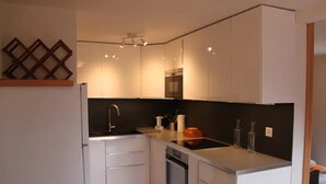A compact kitchen with white cabinetry, a black backsplash, and a stainless steel sink. - Outside: 4-person chalet with balcony, terrace with garden furniture, breathtaking views of the Val (St-Luc)