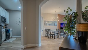 Une cuisine moderne avec des meubles blancs, un four à micro-ondes et un coin repas comprenant une table et des chaises en bois.