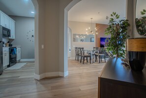 A modern kitchen with white cabinets, a microwave, and a dining area with a wooden table and chairs.