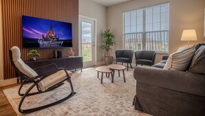 Un salon comprenant un téléviseur à écran plat, un fauteuil à bascule, un canapé, une table basse et une plante en pot.