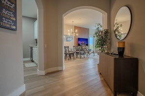 A modern interior with a dining area, a TV, and a decorative mirror.