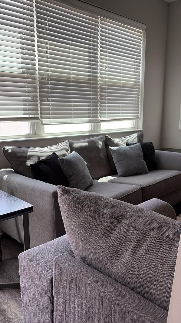 A living room with a grey sofa, a matching armchair, and a small table. - Spacious 4BR Kissimmee Townhome, perfect for family getaways in Osceola County. (Kissimmee)