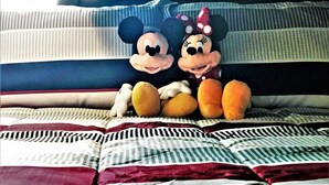 Un lit avec des peluches à l’effigie de Mickey et Minnie Mouse.