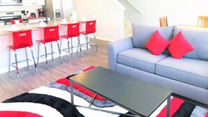 Un salon moderne avec un canapé gris, des coussins rouges et une table basse noire.