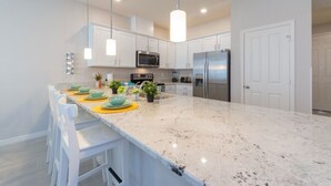 A modern kitchen with white cabinets, stainless steel appliances, and a granite countertop.