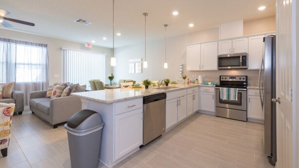 A modern kitchen with white cabinets, stainless steel appliances, and a central island.