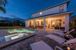 A modern house with a swimming pool, outdoor seating, and a patio area.