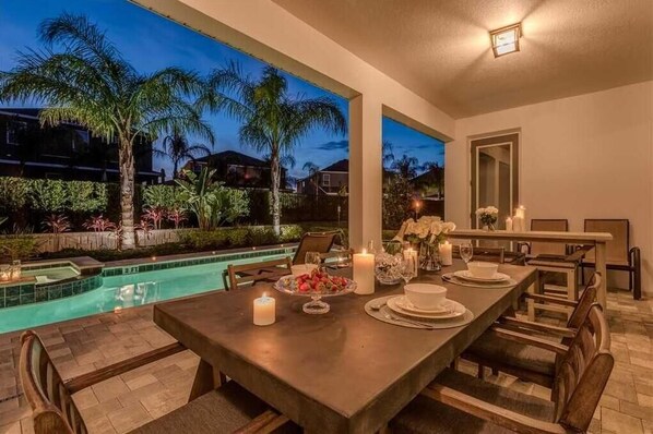 A dining area with a pool view, a table set for four, and a large mirror on the wall.