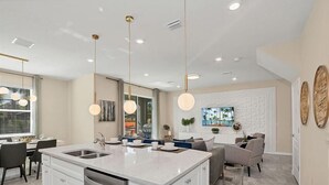 A modern kitchen with a central island, dining area with chairs, and a living space with a sofa and coffee table.