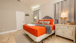 A bedroom with a bed, nightstand, lamp, and curtains. - Spacious 4-bedroom home in Kissimmee, perfect for family getaways! (Kissimmee)