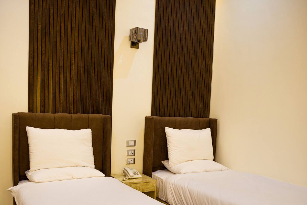 Two single beds with wooden headboards and white bedding in a hotel room.