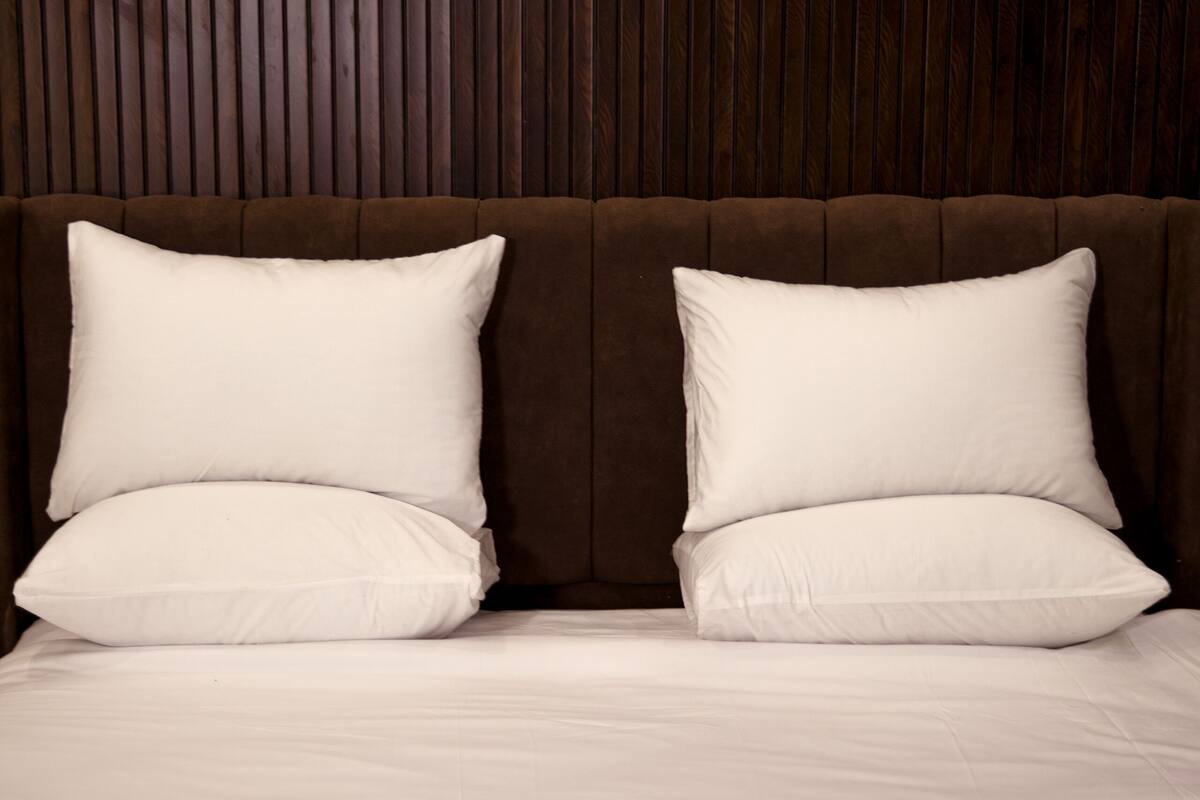 A neatly made bed with two pillows and a folded towel.