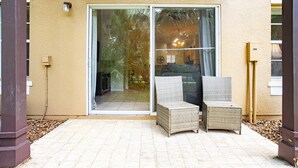 A patio with two wicker chairs, a sliding glass door, and a small table. - Charming 3-bedroom townhome in Kissimmee, perfect for family getaways! (Kissimmee)