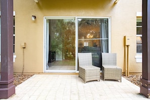 A patio with two wicker chairs, a sliding glass door, and a small table. - Charming 3-bedroom townhome in Kissimmee, perfect for family getaways! (Kissimmee)